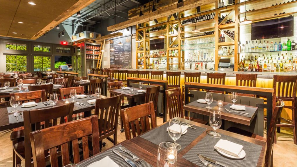 Interior view of Market Bistro featuring neatly set wooden tables and chairs, a well-stocked bar, and warm lighting