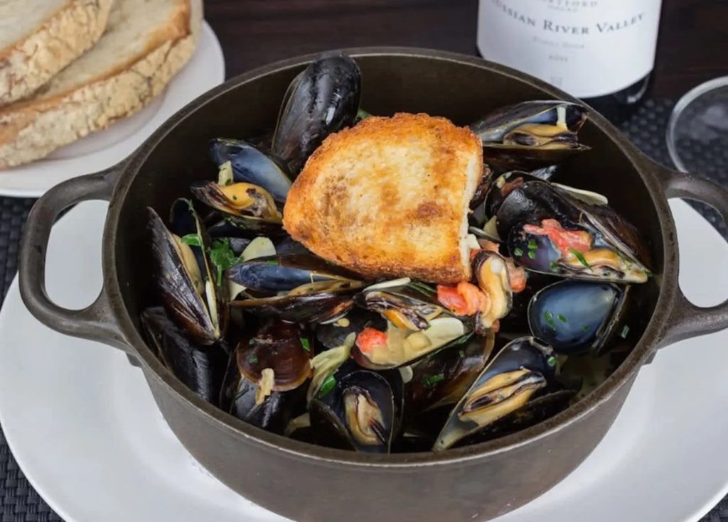 Pot of mussels served with toasted bread and a side of sliced bread at Market Bistro