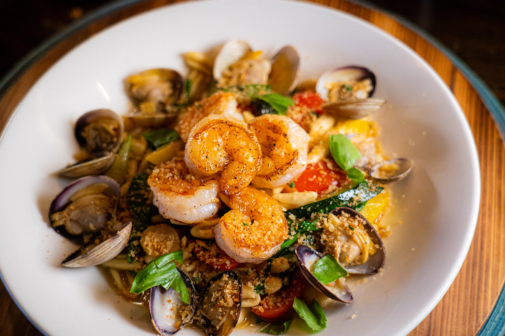 Seafood pasta dish with shrimp, clams, and vegetables garnished with fresh basil at Market Bistro